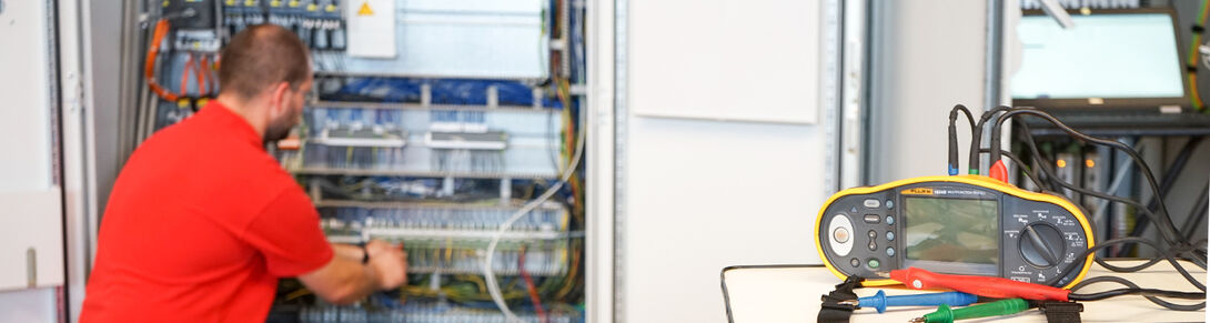 Employee during the electrical installation at the control cabinet